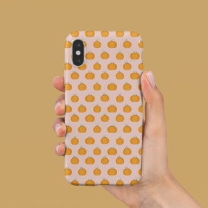 May include: A pink phone case with a pattern of orange pumpkins.