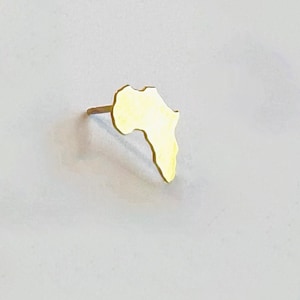 Puede incluir: Un pendiente de color dorado con forma del continente africano.