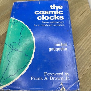 May include: A blue book titled "The Cosmic Clocks: From Astrology to a Modern Science" by Michel Gauquelin with a foreword by Frank A. Brown, Jr. The cover features a green map of South America.