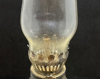 May include: A clear glass oil lamp with a silver-colored metal top and a decorative, cut-glass base.