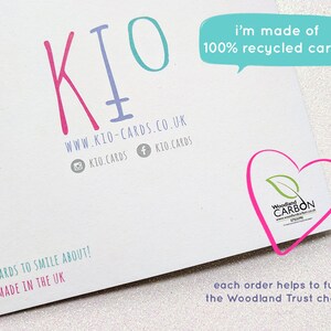 May include: White card with the KIO logo in pink and teal. Text includes "i'm made of 100% recycled card :)" and "Cute cards to smile about! Handmade in the UK." A heart-shaped logo with "Woodland CARBON" is also visible.