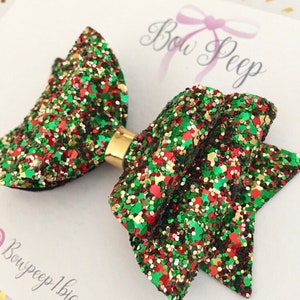 Puede incluir: Un lazo de purpurina verde, rojo y dorado con un clip dorado. El lazo está hecho de un material suave y brillante y es perfecto para agregar un toque de alegría festiva a cualquier atuendo.