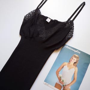 May include: Black sleeveless top with lace trim and a V-neckline. The top is made from a soft, stretchy fabric and has a relaxed fit. The label on the top reads "Attimaglia".