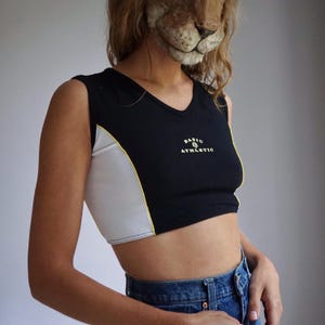 May include: Black and white cropped tank top with yellow trim and the text "BASIC & ATHLETIC" on the front.