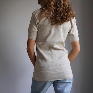 May include: A light grey short-sleeved shirt with a mock neck.