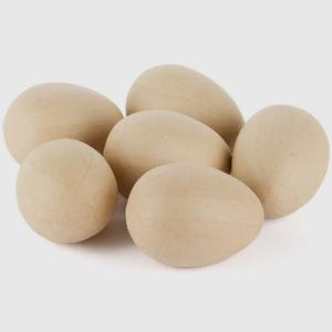 May include: A cluster of six light brown, egg-shaped objects. The eggs have a smooth, matte finish and are arranged in a loose grouping. The eggs are a neutral color, suitable for crafts or decorative purposes.