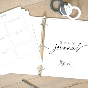 May include: A white binder with the text "BABY journal" and the name "Aiden" written on it. The binder is open to a page with the title "Hello, World!" and spaces for recording details about the baby's birth.
