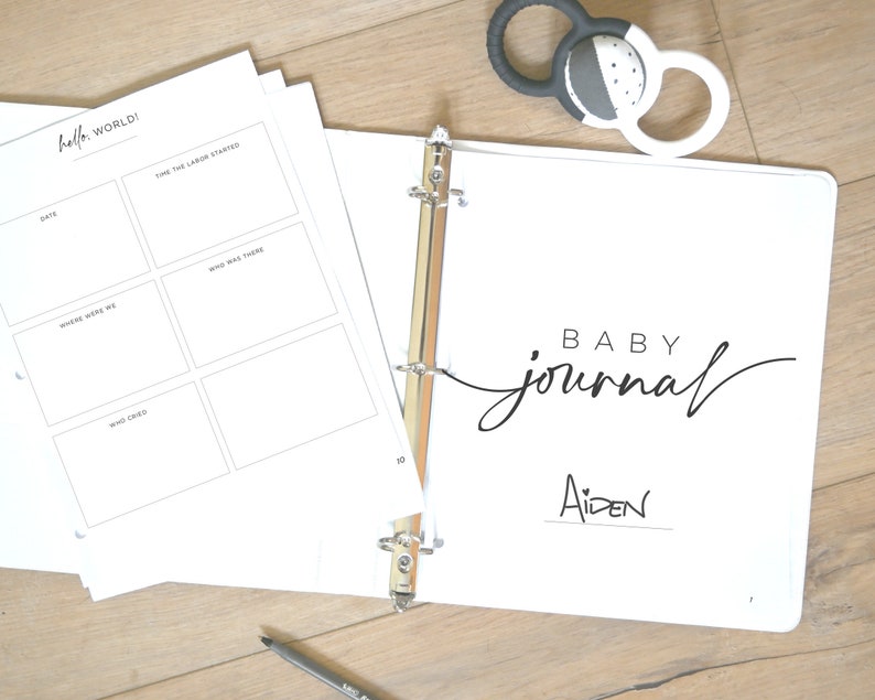 May include: A white binder with the text "BABY journal" and the name "Aiden" written on it. The binder is open to a page with the title "Hello, World!" and spaces for recording details about the baby's birth.