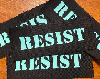 RESIST - Patch preto costurado com texto azul-petróleo