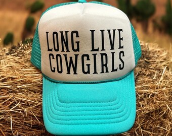 Op de afbeelding: Een turquoise en witte truckercap met een zwart geborduurd ontwerp met de tekst "Long Live Cowgirls".