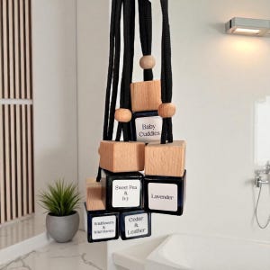 以下が含まれることがあります： 黒いコード、木製のビーズ、木製のブロックが付いた、吊り下げ式の車用芳香剤。各ブロックには、ラベルが付いた小さな濃い青色のボトルが付いています。「Baby Cuddles」、「Sweet Pea & Ivy」、「Lavender」などの香りがあります。
