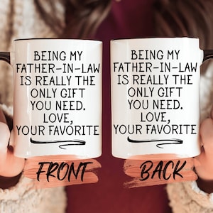 May include: Two white coffee mugs with black handles. The front of the mug says "Being my father-in-law is really the only gift you need. Love, your favorite". The back of the mug says "Being my father-in-law is really the only gift you need. Love, your favorite".