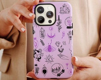May include: A purple phone case with a black and white design of various mystical symbols, including a crescent moon, a crystal, a skull, a moth, and a hand with an eye.