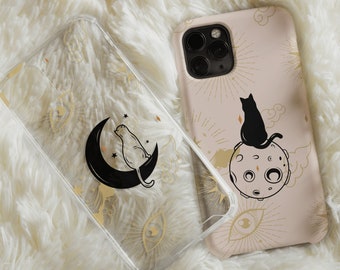 May include: Two clear phone cases featuring a black cat design. One case depicts a black cat sitting on a crescent moon with stars. The other case shows a black cat sitting on a moon with a pink background and gold accents.
