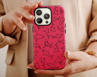 May include: A pink iPhone case with a black outline of sharks repeated across the surface.