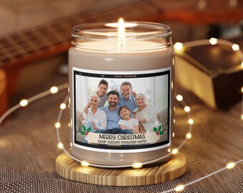 May include: A lit candle in a glass jar with a family photo on the label. The label reads "Merry Christmas" with space for a custom message. The candle sits on a wooden coaster, surrounded by string lights.