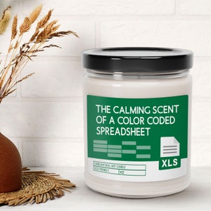 May include: A white soy candle with a green label that reads "The Calming Scent of a Color Coded Spreadsheet" and a green icon of a document with the letters "XLS". The candle is 9 oz and eco-friendly.