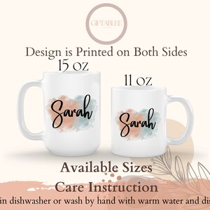 Op de afbeelding: Twee witte keramische mokken met een aquarelontwerp in tinten perzik en blauw. De mokken zijn bedrukt met de naam "Sarah" en zijn verkrijgbaar in de maten 11 oz en 15 oz. De tekst "Design is Printed on Both Sides" is ook zichtbaar.