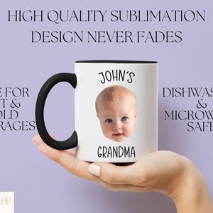A hand holding a white mug with a black handle, featuring a photo of a baby's face.