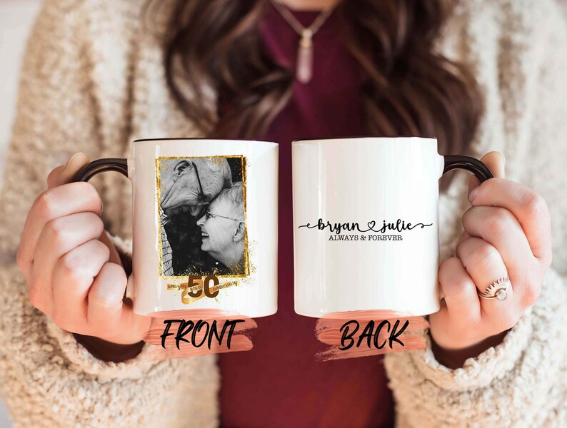 May include: White ceramic mug with a black handle. The front of the mug features a black and white photo of a couple with a gold 50th anniversary design. The back of the mug has the text "Bryan & Julie Always & Forever" in black.