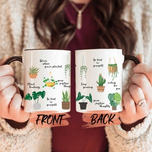 May include: White ceramic mug with a black handle. The mug has a green and yellow plant design with inspirational quotes. The front of the mug says "bloom where you're planted, plant kindness, grow positive thoug, be leaf in yourself". The back of the mug says "be leaf in yourself, keep growing, rooting for you, grow positive thoughts".