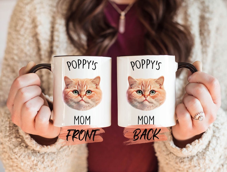 Puede incluir: Taza de cer&aacute;mica blanca con asa negra. La taza tiene una imagen de un gato con el texto "Poppy's Mom" en la parte delantera y trasera.