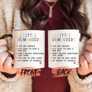 a woman holding two coffee mugs that say, little reminderers