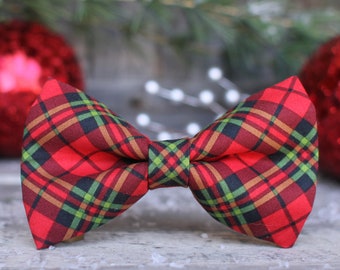 May include: A red, green, and black plaid bow tie. The bow tie is made of fabric and has a classic bow shape.