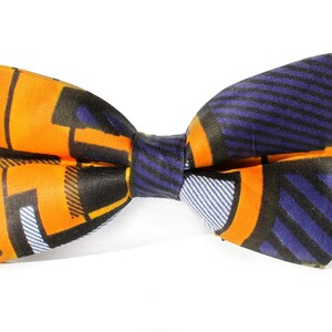 May include: A bow tie with a geometric pattern in orange, blue, and black.