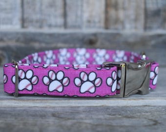 May include: Pink dog collar with a white baseball paw print pattern and a silver buckle.
