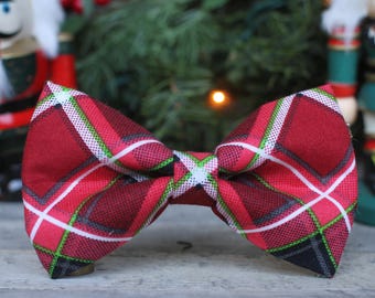 May include: A red, green, white, and black plaid bow tie. The bow tie is made of a soft, textured fabric.