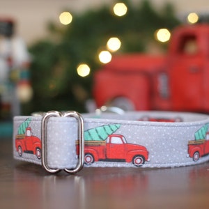 Könnte beinhalten: Ein graues Hundehalsband mit weißem Punktmuster und einem roten Lastwagen, der einen grünen Weihnachtsbaum transportiert. Das Halsband hat eine silberne Schnalle.