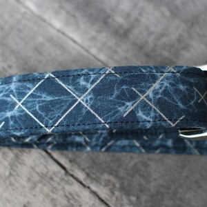 Peut inclure: Un collier pour chien bleu et argent avec un motif g&eacute;om&eacute;trique. Le collier a une boucle argent&eacute;e et est fait de tissu.