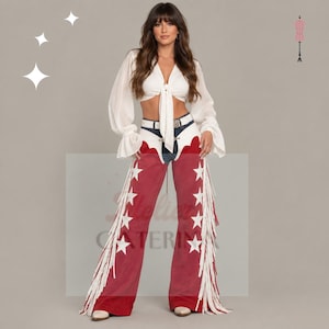 May include: A white long-sleeved blouse with a front tie closure paired with red suede chaps featuring white star appliqués and long white fringe along the outer legs. The chaps are worn over blue denim jeans with a white belt and white boots.