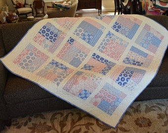 Handmade quilt for the perfect baby gift done in pale pink and blue fabrics with geometric designs, white flannel back, machine quilted
