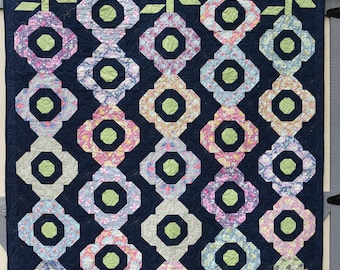 Beautiful handmade navy quilt with bright flowers, with a navy backing, machine quilted in a dragon fly pattern