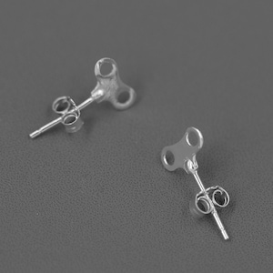 May include: Two silver-colored stud earrings. Each earring features a key-shaped design with a post and butterfly backing. The earrings are displayed on a gray surface, showcasing their simple, yet elegant design. These earrings are perfect for everyday wear.