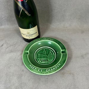 May include: Green ceramic ashtray with a white image of a building and the text "Abbaye d'Hautvillers" and "Moët et Chandon Maison Fondée en 1743".