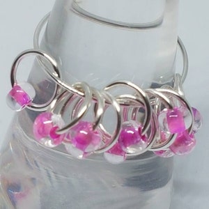 May include: A silver ring featuring pink and white beads. The ring is crafted from wire and has a straightforward design.