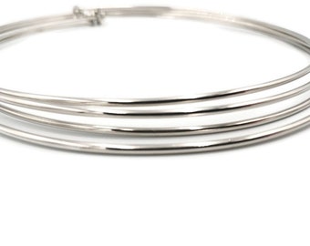 May include: A set of three silver-toned metal bangles, stacked on top of each other. The bangles are smooth and shiny.