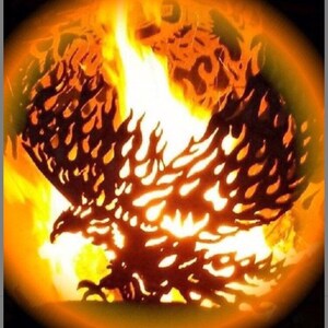 May include: A metal fire pit shaped like an eagle with flames burning inside. The eagle is silhouetted against the orange flames.