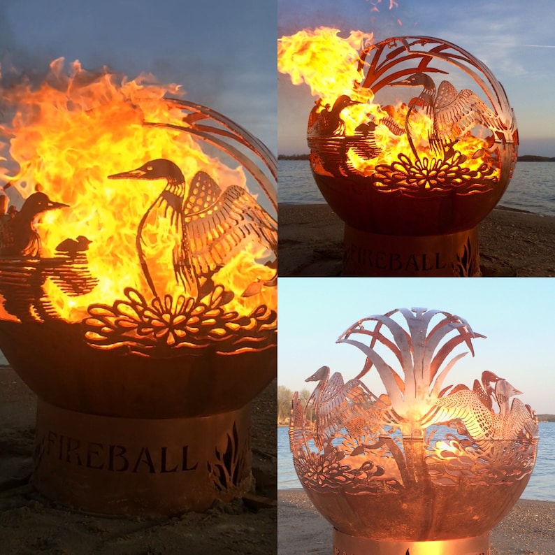 May include: A metal fire pit shaped like a sphere with a cut-out design of a loon and water plants. The fire pit is lit and has flames coming out of the top. The fire pit is sitting on a base with the word "FIREBALL" engraved on it.