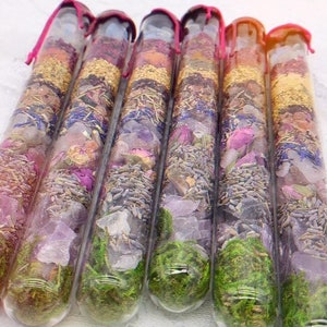 Puede incluir: Seis tubos de vidrio llenos de flores secas, hierbas y cristales. Los tubos están sellados con una tapa de cera roja.