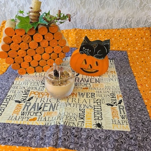 Può includere: Un runner da tavolo a tema Halloween con uno schema di colori arancione e nero. Il runner presenta una varietà di parole e immagini a tema Halloween, tra cui zucche, pipistrelli, ragni e streghe. C'è una piccola statuetta di gatto nero seduta su una zucca e un barattolo di vetro con una candela all'interno.