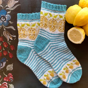 Könnte beinhalten: Ein Paar blaue und weiße gestreifte Stricksocken mit einem Zitronenmuster. Die Socken sind aus weichem Garn gefertigt und haben eine bequeme Passform.