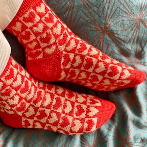 Peut inclure: Une paire de chaussettes rouges avec un motif de cœurs blancs. Les chaussettes sont tricotées et ont une sensation douce et confortable.