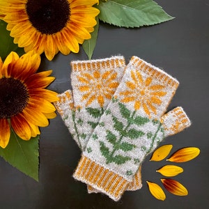 May include: A pair of knitted fingerless gloves featuring a sunflower design in shades of yellow, green, and white. The gloves are crafted from a soft, textured yarn and offer a comfortable fit.
