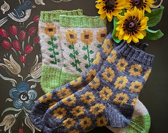 May include: A pair of knitted socks with a floral pattern. One sock is green and white with a floral design, the other is dark blue with a yellow floral pattern.