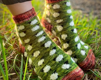 May include: A pair of green and white patterned socks with red and orange accents at the top. The socks are made of a soft, knitted fabric and have a comfortable fit.