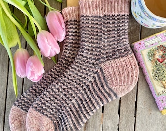 May include: A pair of pink and black striped knitted socks. The socks are made with a fine yarn and have a ribbed cuff.